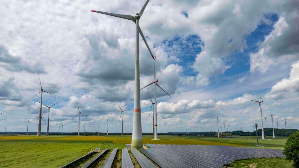 A wind farm with solar panels on the ground