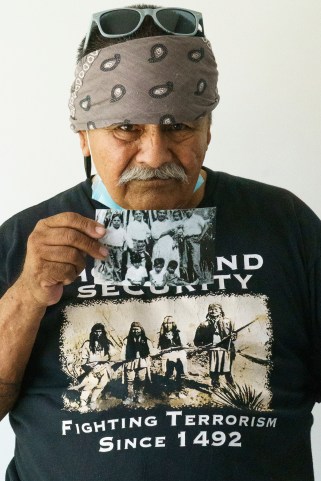 Man with a bandana on his head holding an old black and white photo.