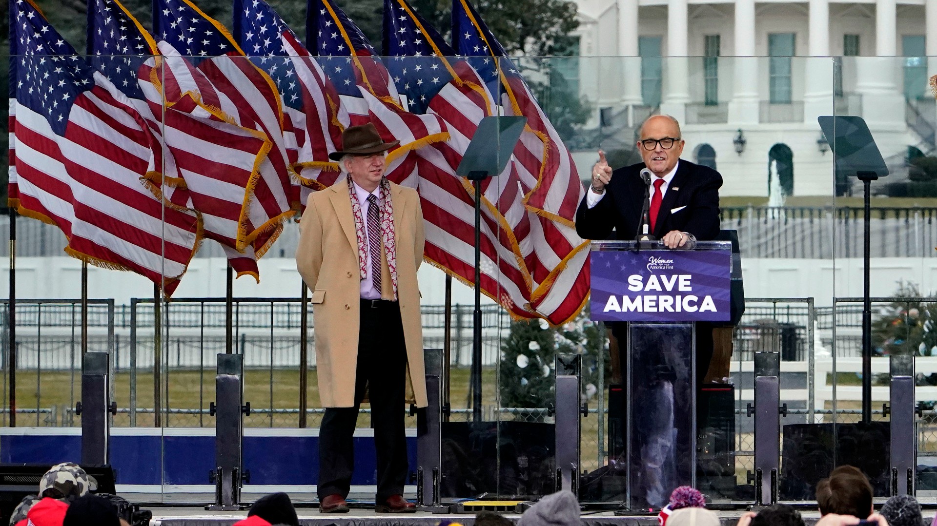John Eastman stands at left as former New York Mayor Rudolph Giuliani speaks in Washington at a rally in support of President Donald Trump, called the "Save America Rally."