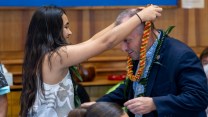 NAVAHINE F, a youth plaintiff in a climate lawsuit against the state of Hawaii, presents Gov. Josh Green with a flower lei.