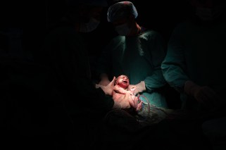 Dark image with a strong light on a newborn baby.