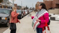 A woman in a keffiyeh offers a 'vote uncommitted' flyer to someone outside a polling place in Hamtramck, Michigan.