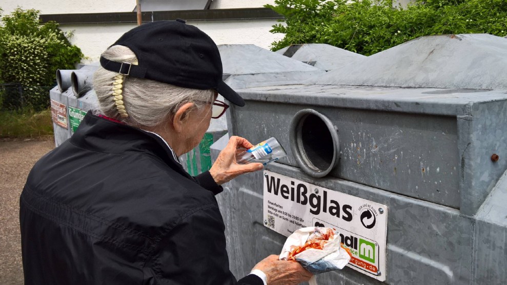 Woman placing glass bottle into recycling container