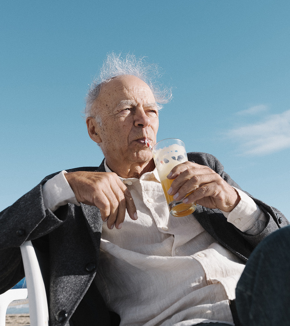 Man sitting in a chair drinking out of a straw.