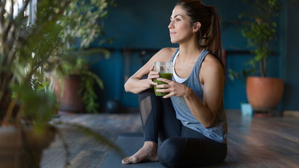 A woman with a glass of green juice