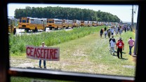 Rally-goers stream past a protestor holding a sign that calls for a ceasefire outside the Kamala Harris and Tim Walz presidential campaign event near Detroit.