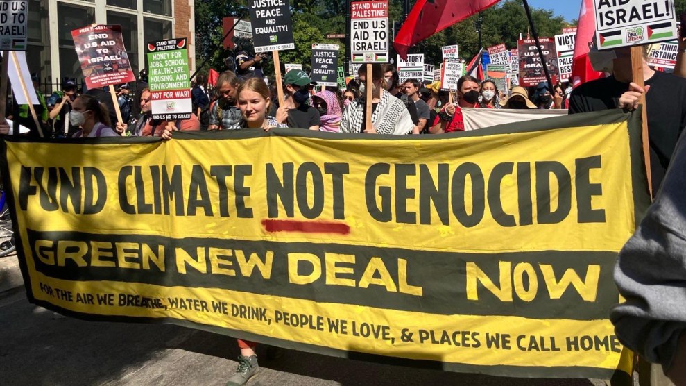 A crowd of Sunrise Movement protestors marches through the streets of Chicago holding signs in protest of genocide and in support of climate funding.