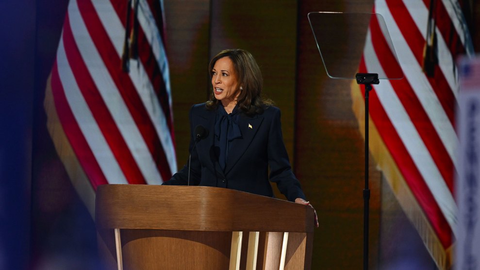 Kamala Harris speaking at a podium with American flags behind her