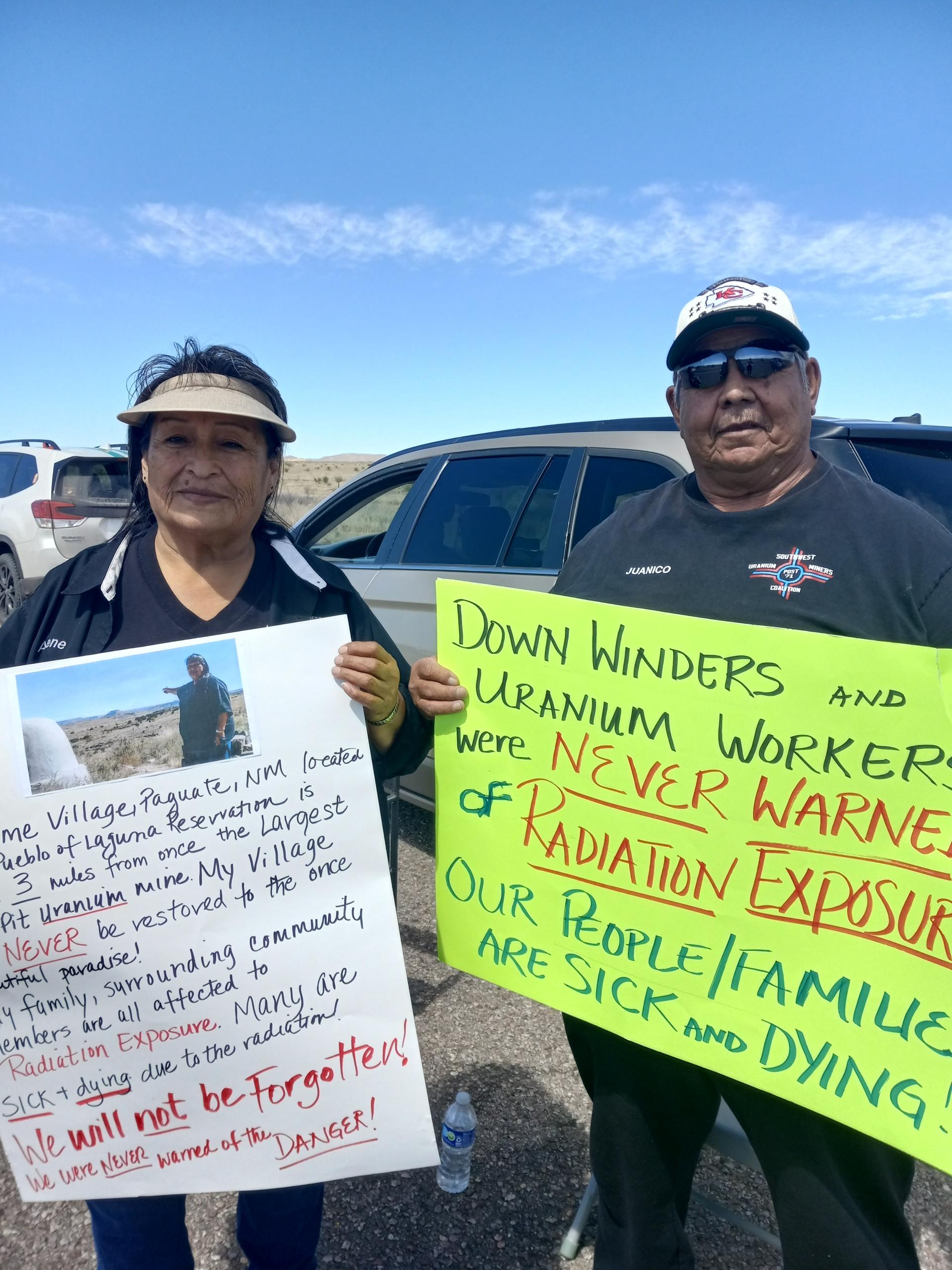 Woman and a man standing outside holding signs