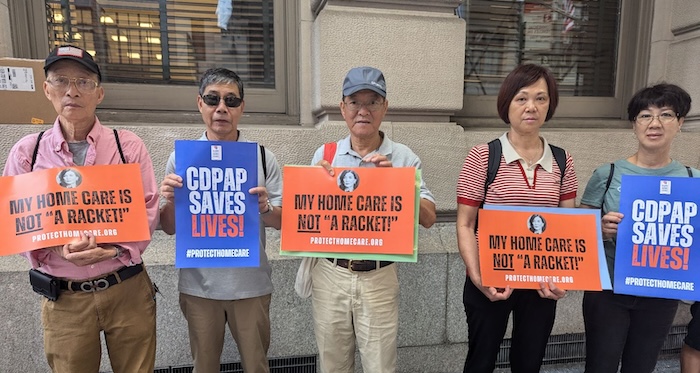 Vijf demonstranten staan ​​op een straat in New York met borden waarop staat: "Mijn thuiszorg is geen oplichterij" En "CDPAP redt levens"
