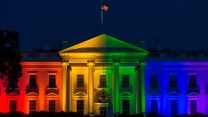 Exterior of the White House lighted in rainbow colors at night.