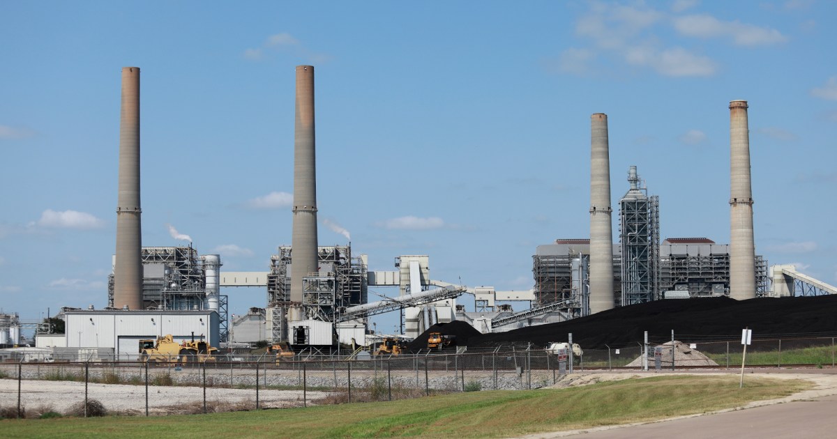 Smokestacks photographed against a blue sky with a smattering of clouds.