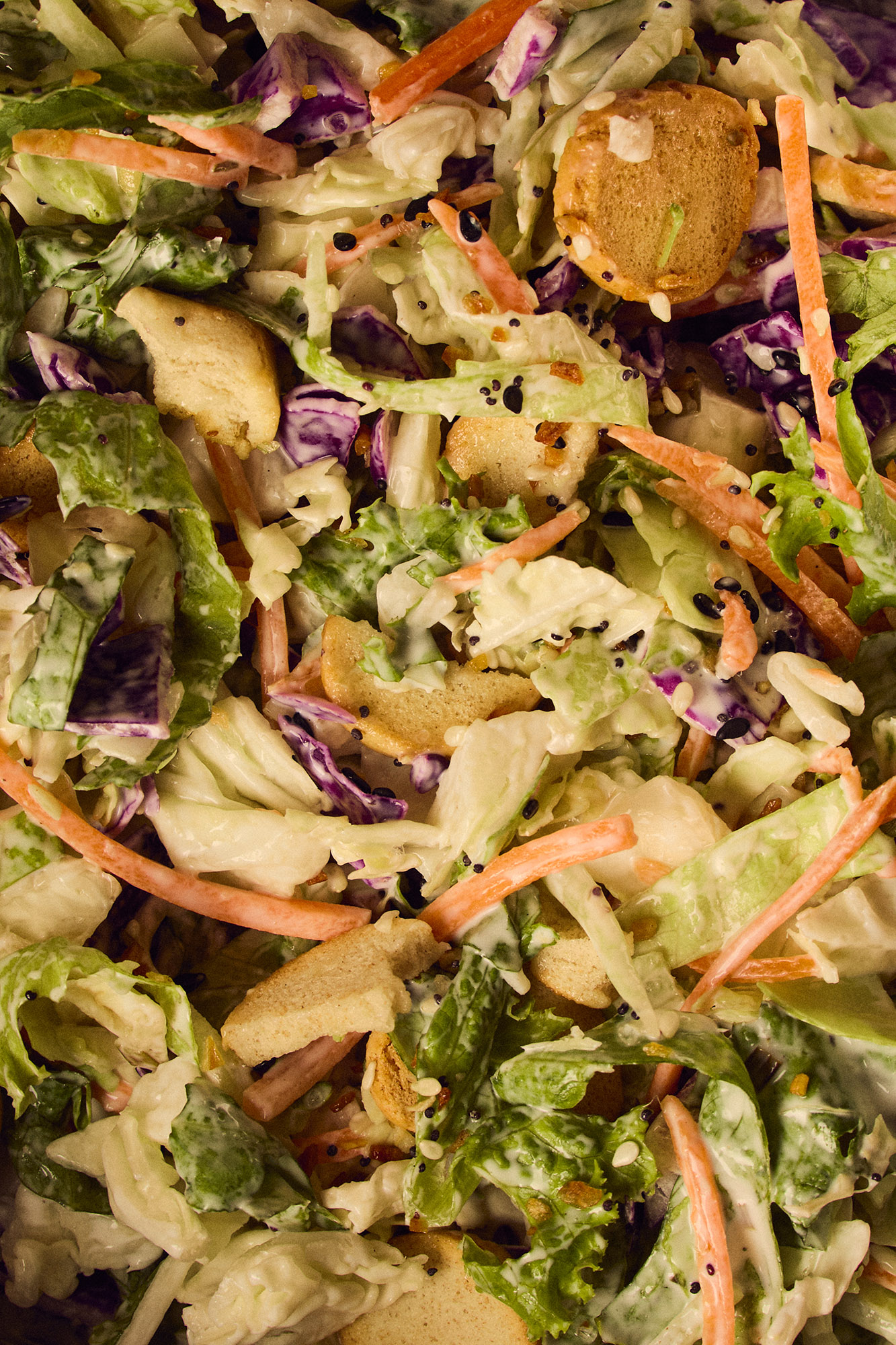 A close-up picture of a salad mixed with dressing and poppy seeds.