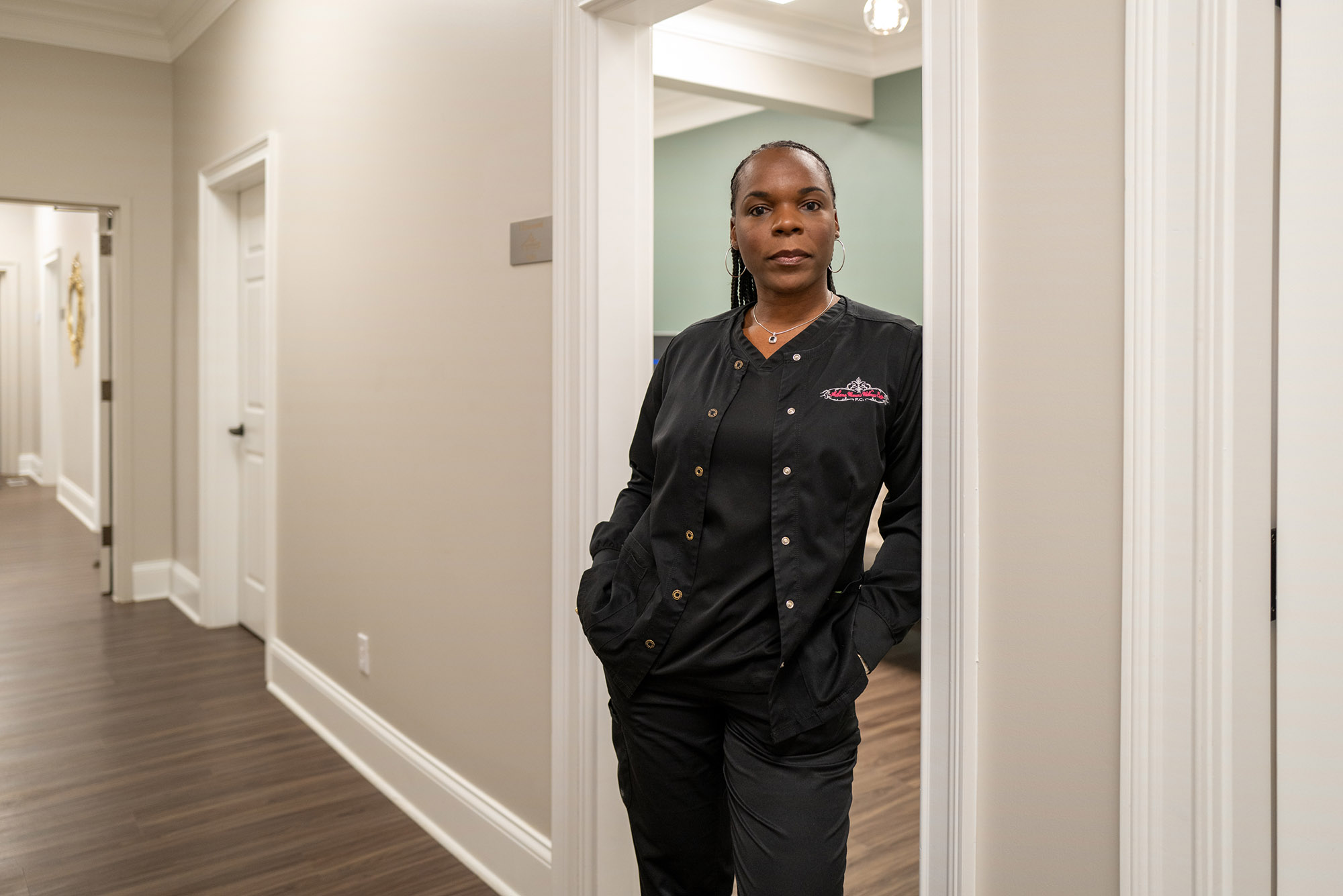 Dr. Yashica Robinson, a Black woman wearing black scrubs, poses for a portrait in her office.