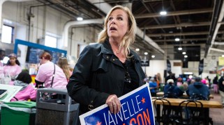 Blond woman holding campaign sign in a market.