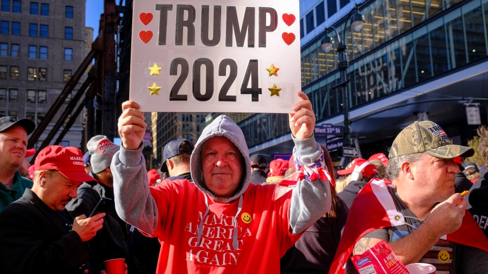 A white man wearing an orange Make America Great Again t-shirt holds a Trump 2024 sign outside Madison Square Garden.