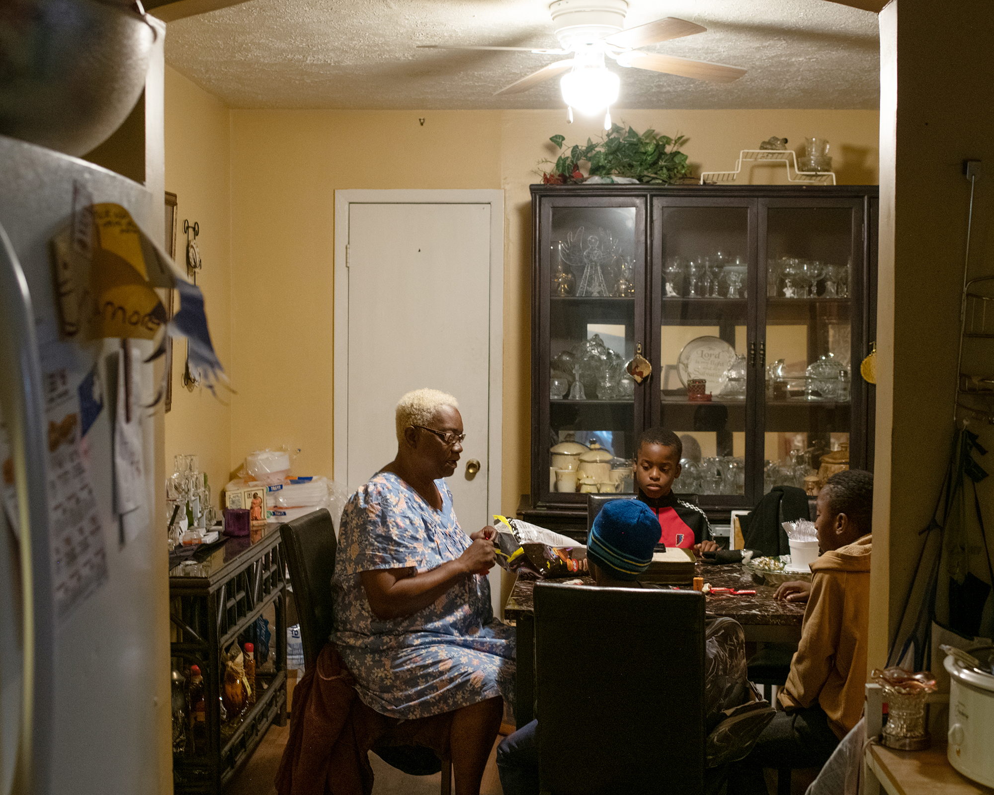 A woman sits at a dining table with three children.