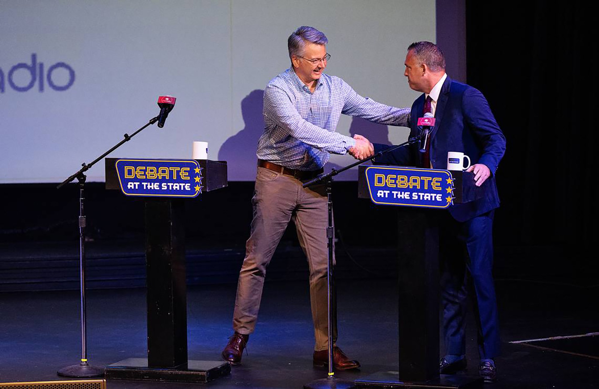 Rep. John Duarte shakes hands on stage with Adam Gray before a debate. 