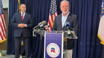 Republican North Carolina Senate leader Phil Berger stands at a press conference podium behind microphones alongside his party Jason Simmons, both wearing dark suits.