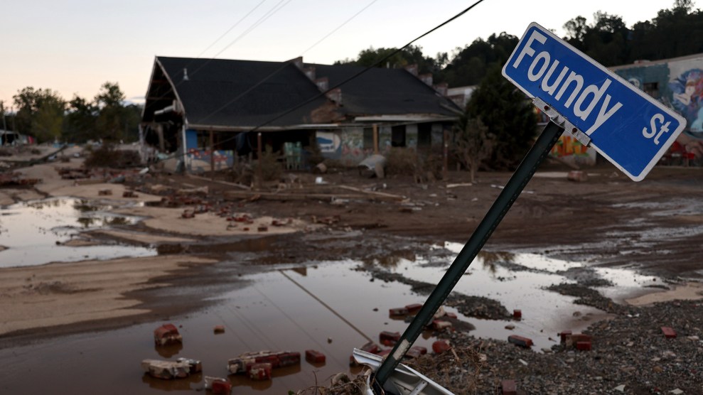 Flooded and devastated town with a broken street sign in the foreground.