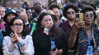 Group of women with one woman crying, holding her hand over her mouth.