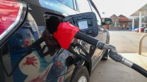 A car is filling up on gas with a red pump handle