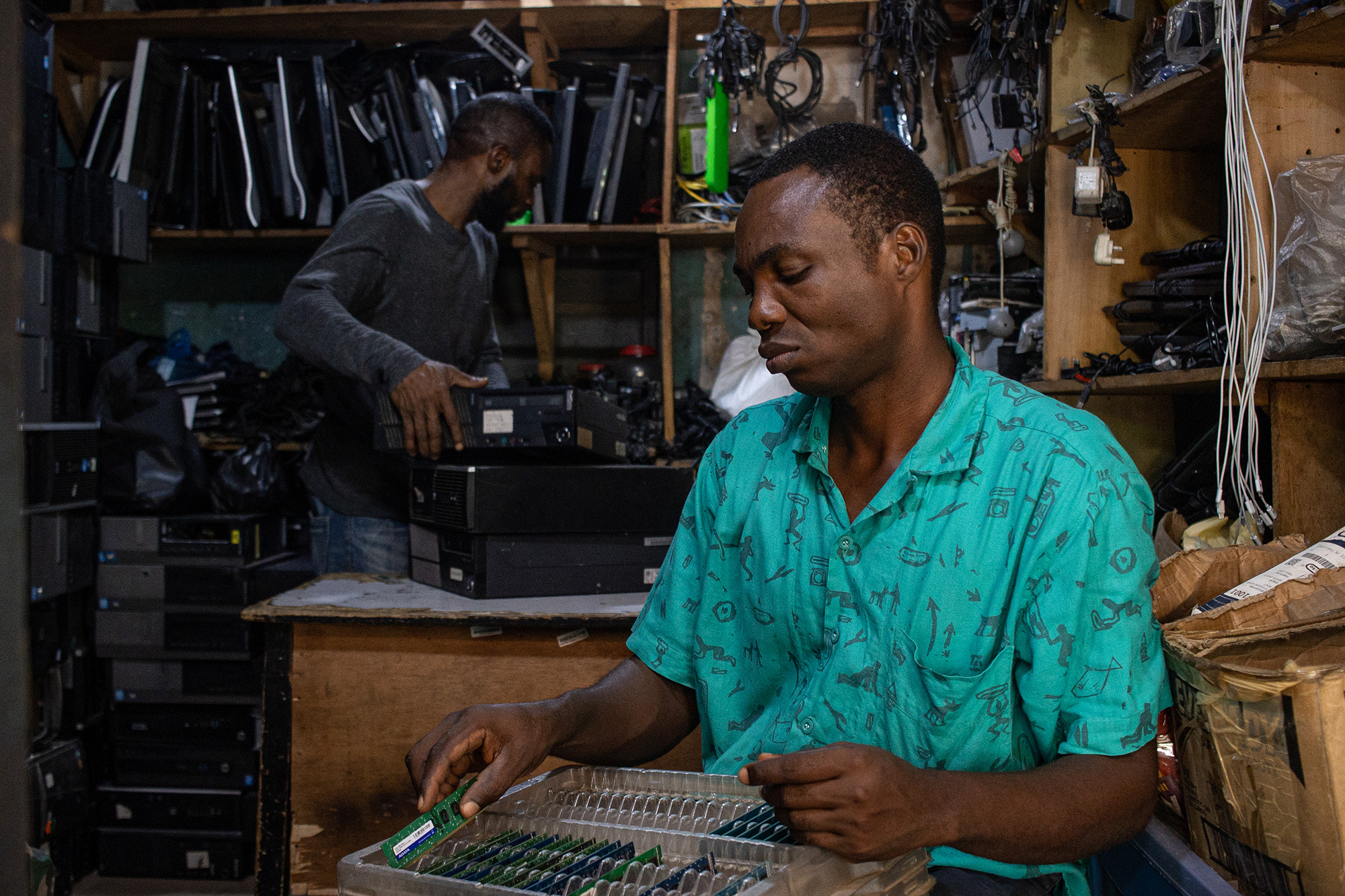 Two men in a shop sorting computer parts.