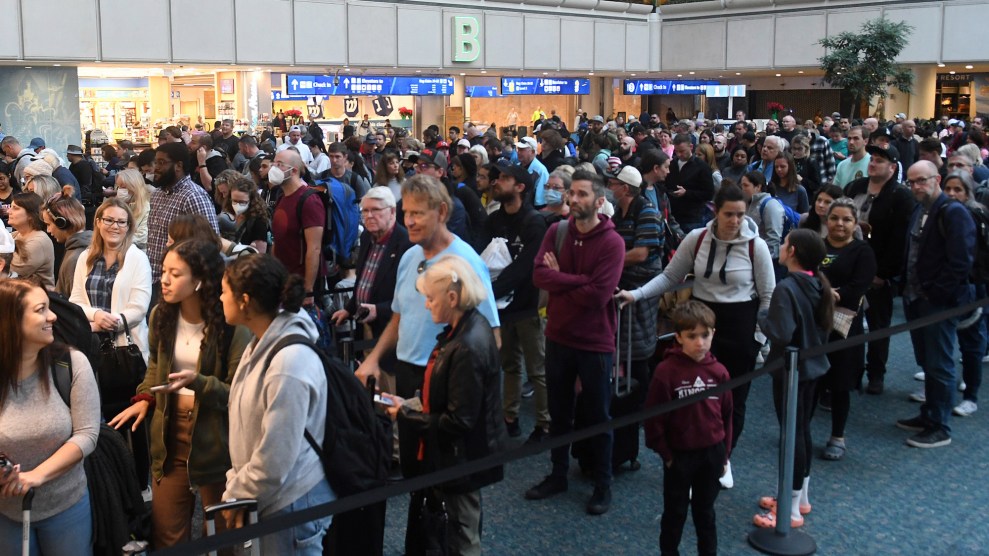 Dozens of peple wait in long lines with baggage.