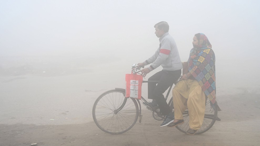 Two people on a bike are partially visible through thick air pollution