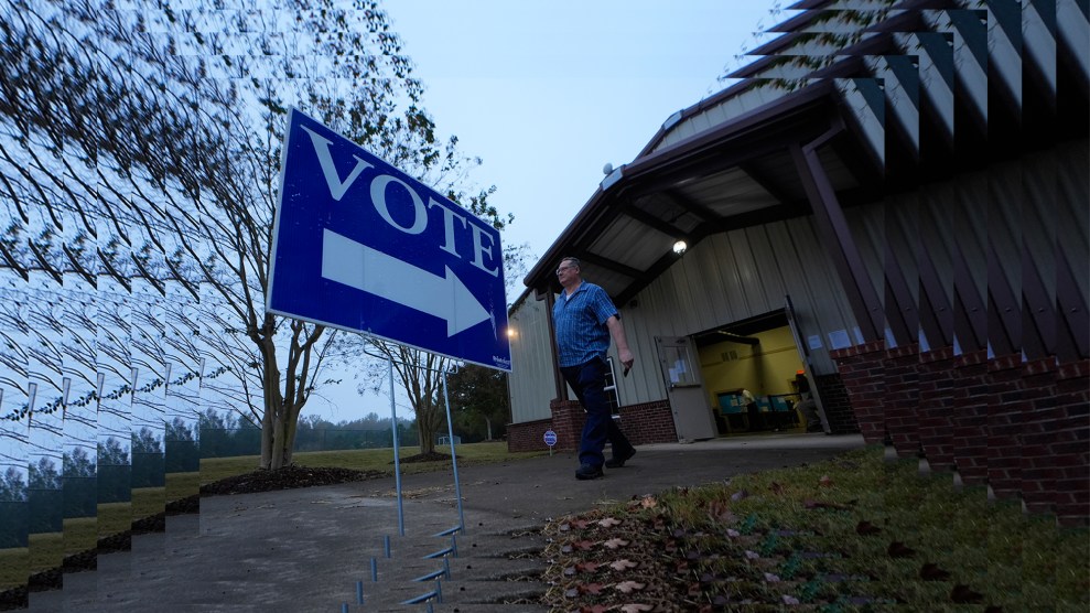 A voter leaves a polling place after voting on November 5, 2024 in Rutledge, Georgia, holding a large blue flag. "VOTE" sign in front of him.