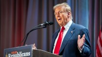 Donald Trump stands on a podium.