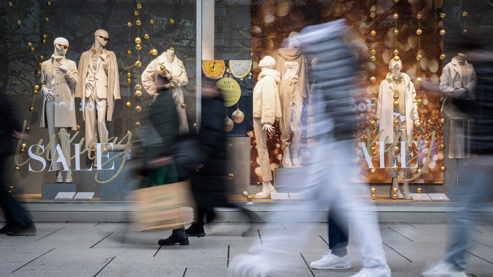 Blurred figures walk past sale signs.