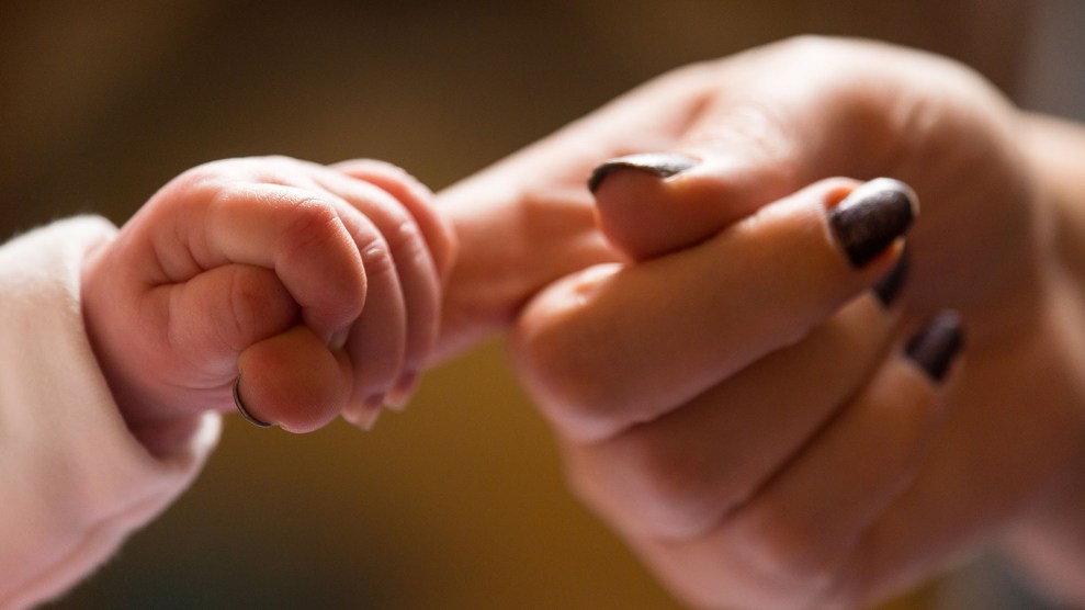 A small baby hand holds a larger parent hand.