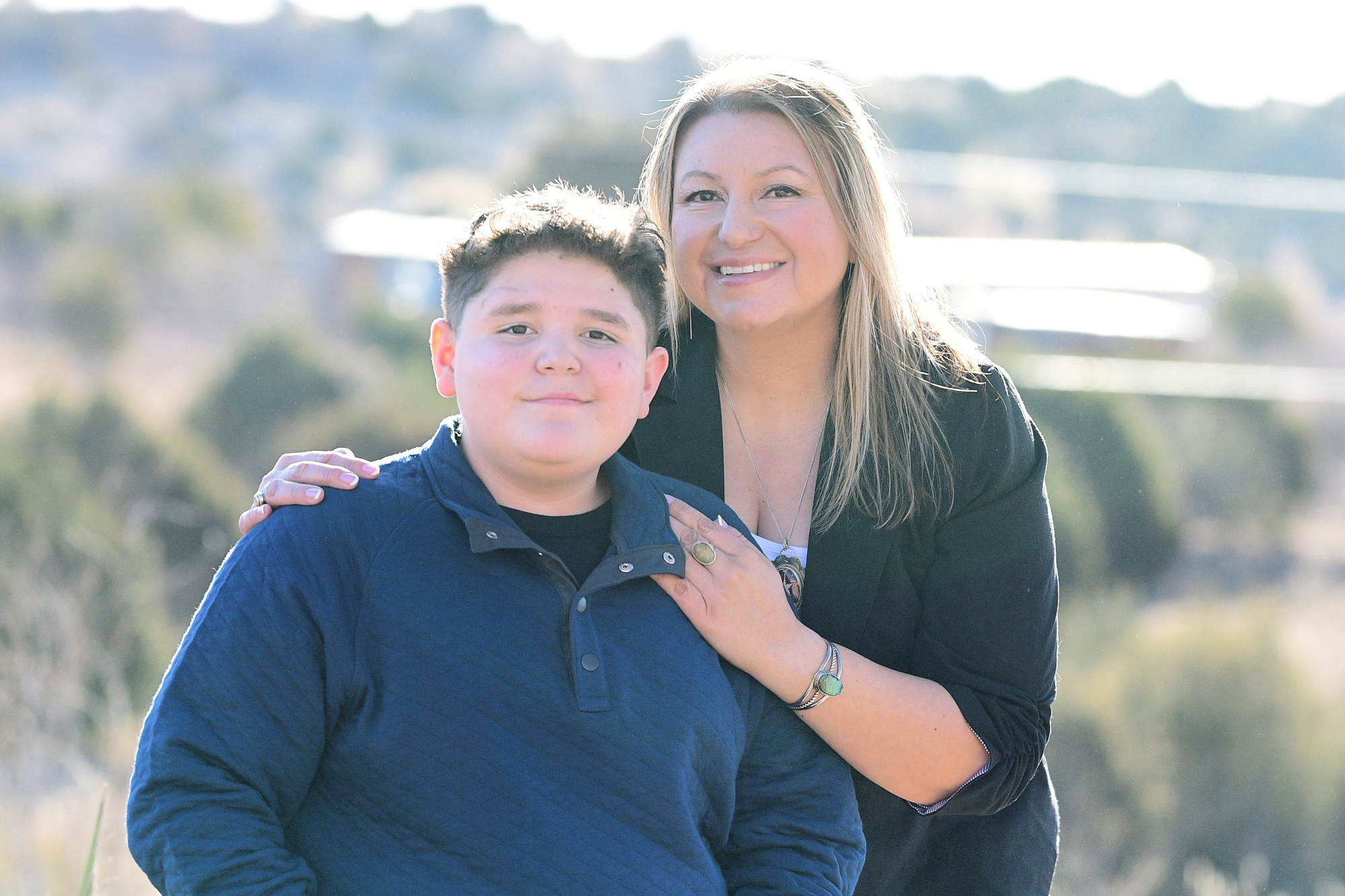 A woman with long hair poses with her teenage son.