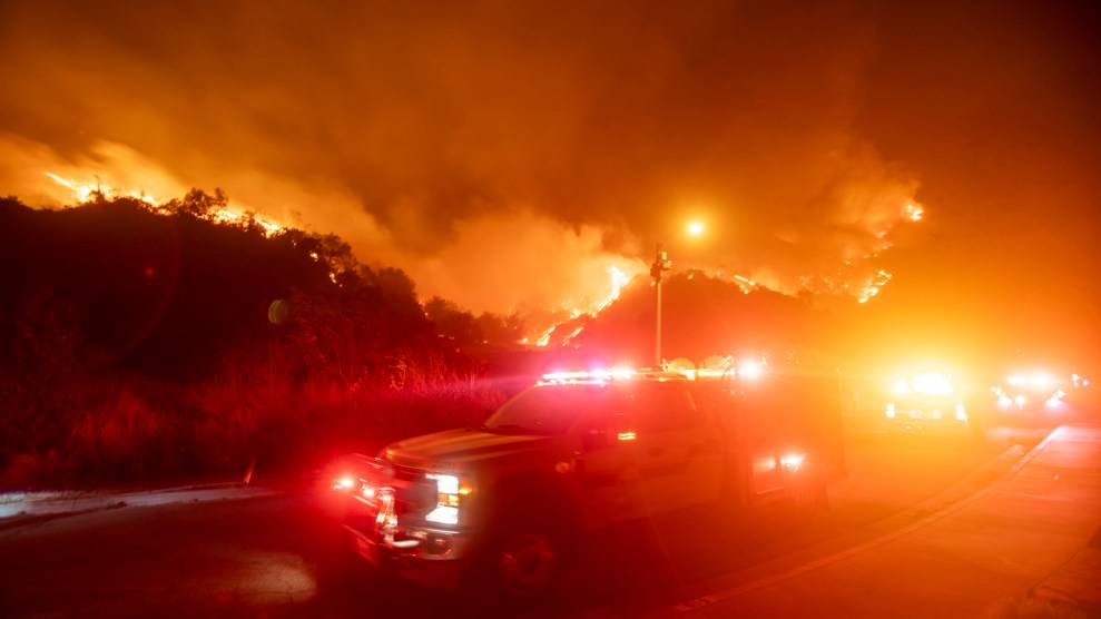 An emergency vehicle flashes red amongst think smoke and fire.