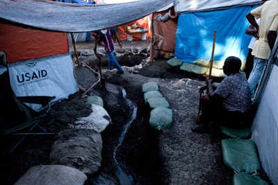Makeshift tent walls include tarps provided by USAID.