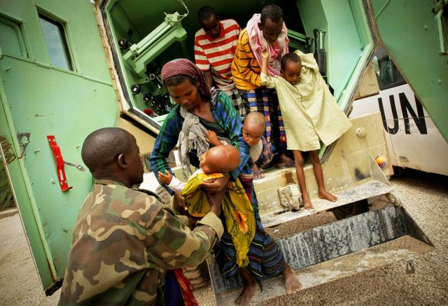 A Somali woman in Mogadishu hands her severely malnourished child to a medical officer of the African Union Mission in Somalia.: Stuart Price/UN/Flickr