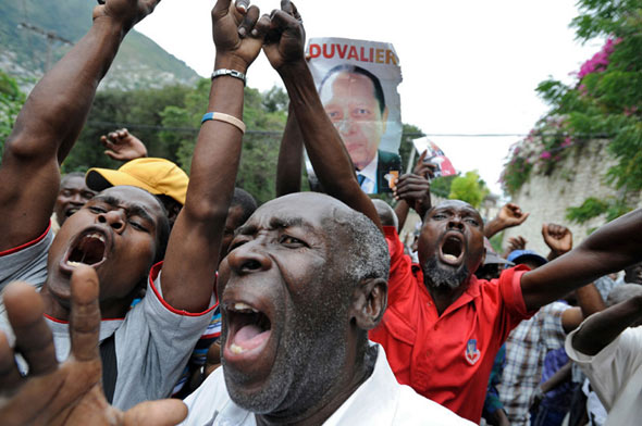 Duvalier supporters react as police take him from his hotel to the courthouse.