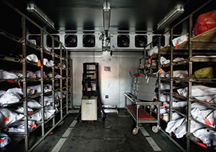 Body bags, many holding unidentified bodies found in the desert, sit in a cooler at the Pima County ME office.