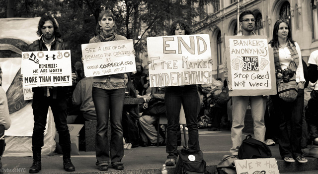 Protesters hold signs in Zuccotti Park.: VBlessNYC/Flickr