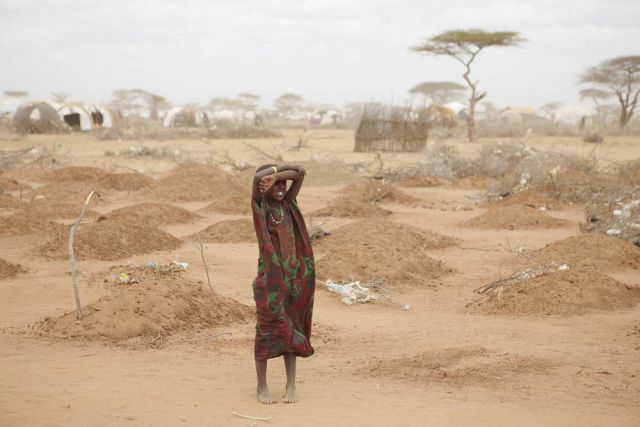 On the edge of the Dadaab refugee camp, a young girl stands amid the freshly made graves of 70 children, many of whom died of malnutrition.: Andy Hall/Oxfam/Flickr